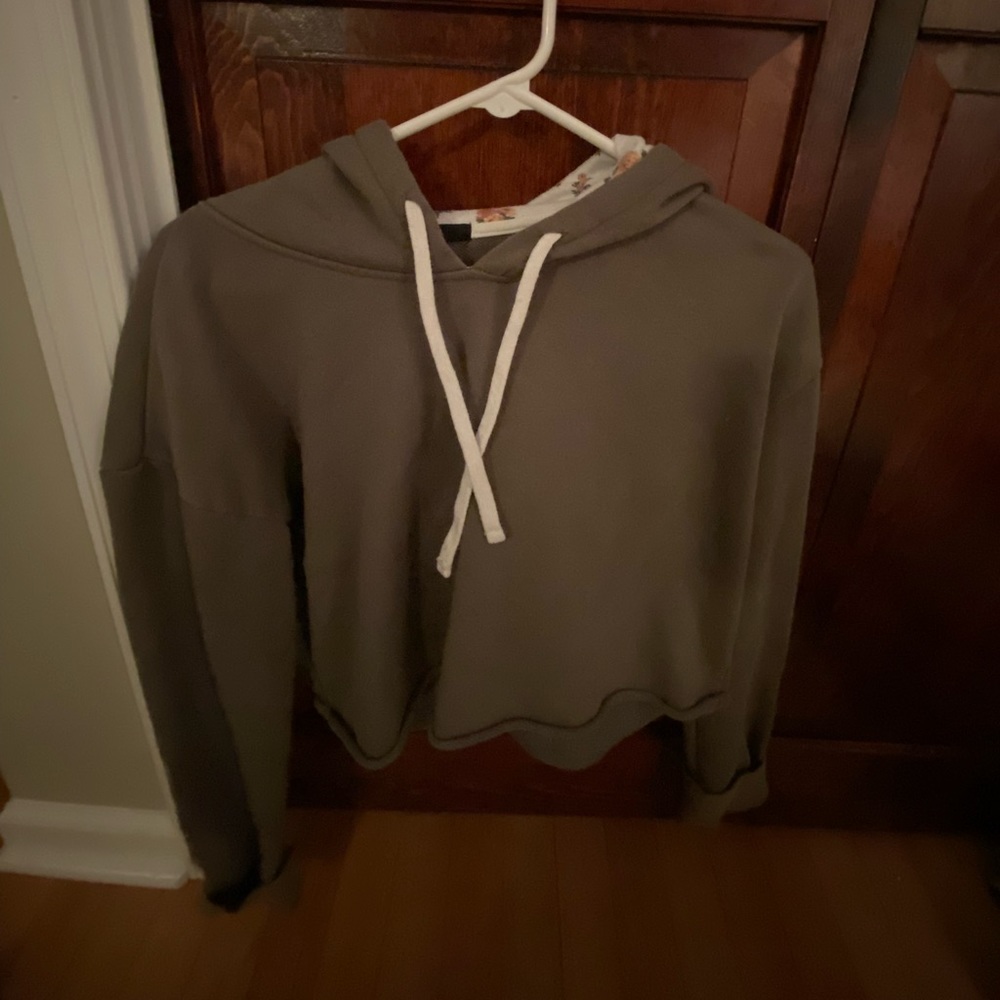 A cropped green hoodie with a floral print inside